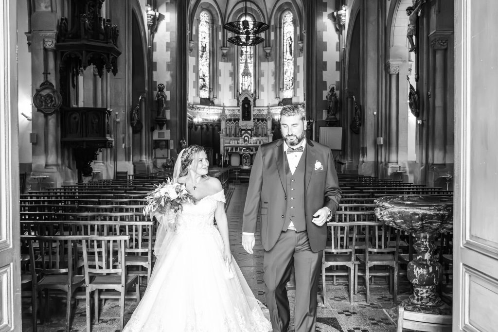Couple de mariés au milieu de la nef d'une église, photographie en noir et blanc
