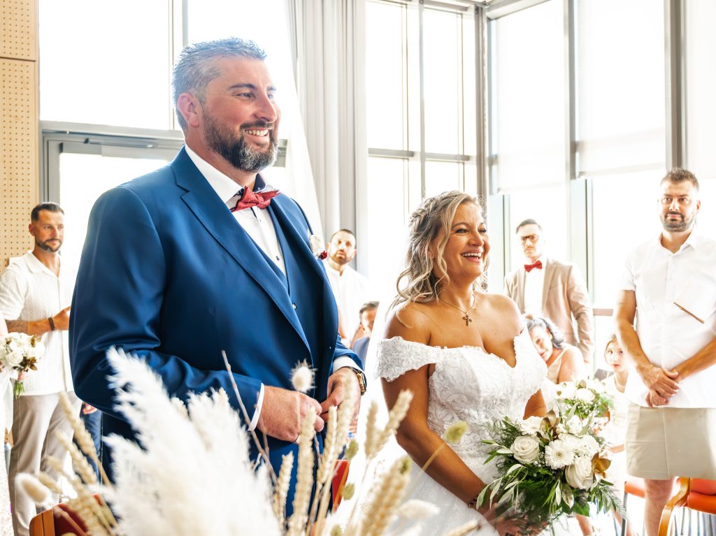 Le marié en costume bleu et la mariée éclatent de rire pendant la cérémonie