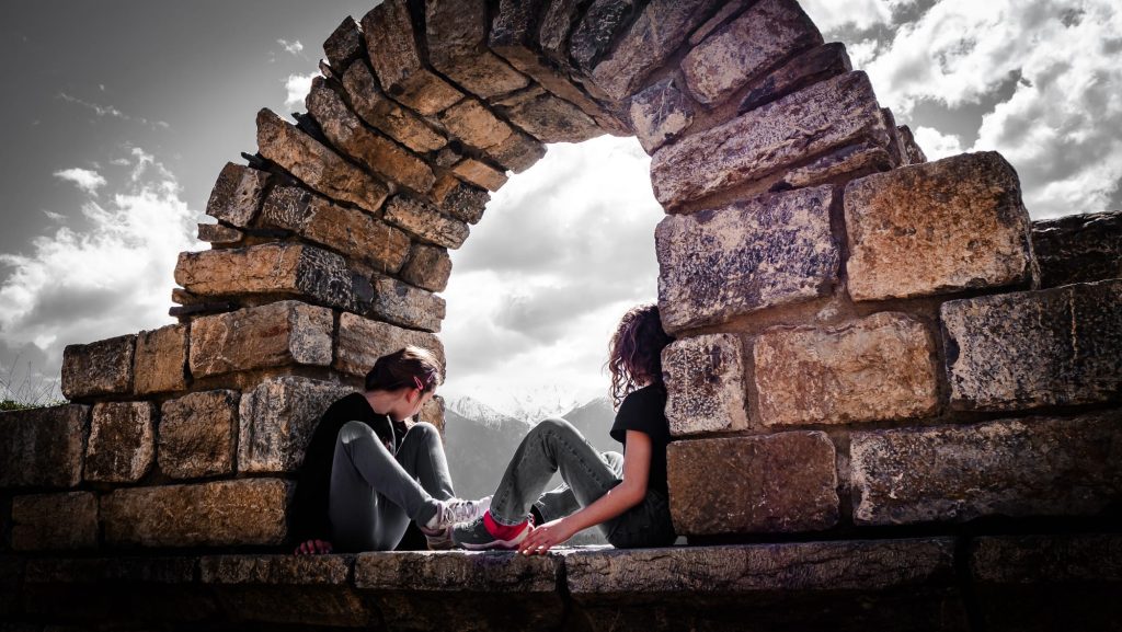 Photographie de couple de mariés sous une arche en pierre en noir et blanc