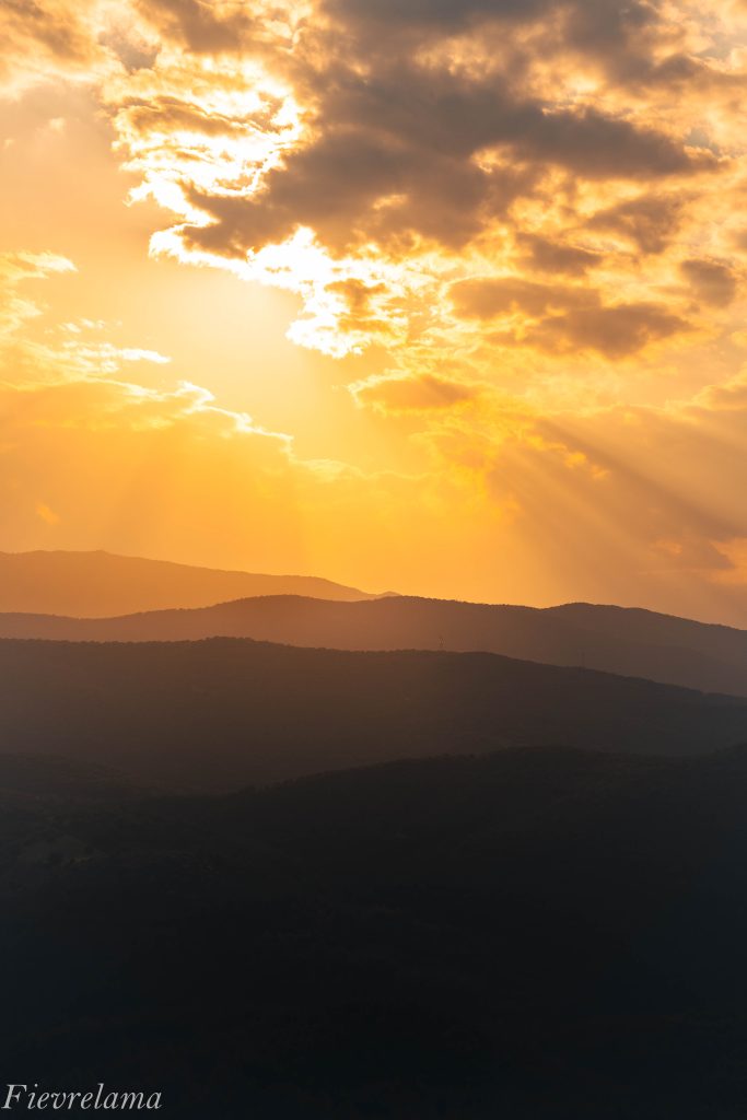 Rayons de soleil traversant les nuages au-dessus de crêtes montagneuses